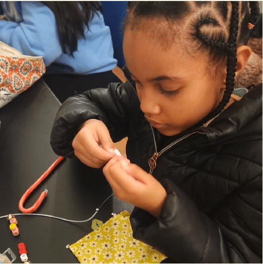 Young girl learning how to make jewelry